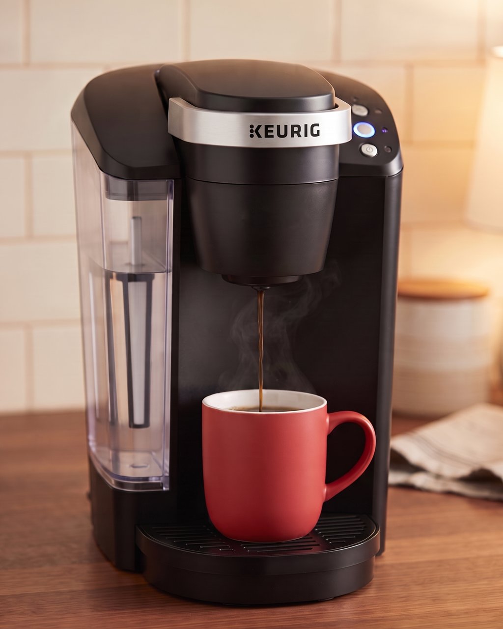 A black Keurig K-Classic pod coffee maker, KEURIG on its silver band, brewing into a red mug on a walnut kitchen counter.